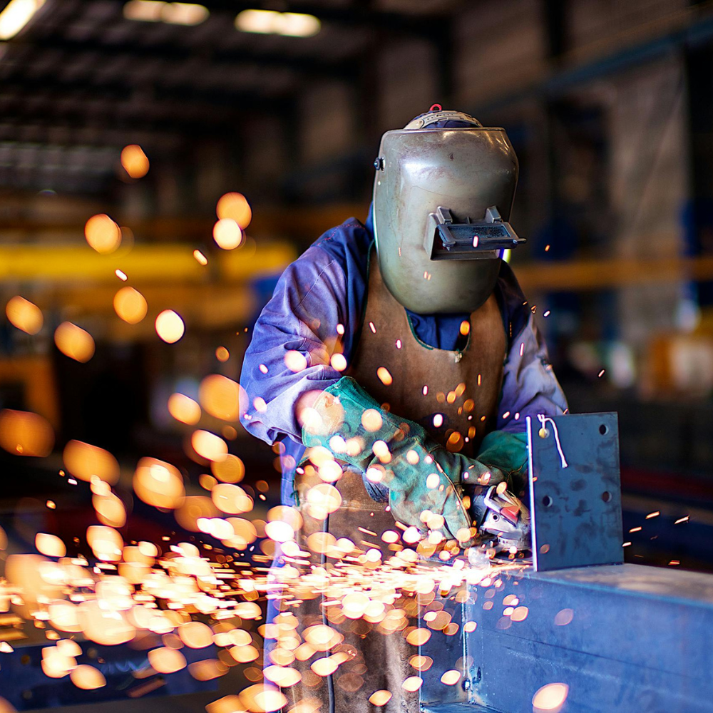 Operatore specializzato in saldatura con dispositivi di protezione individuale durante lavorazione metalli in officina