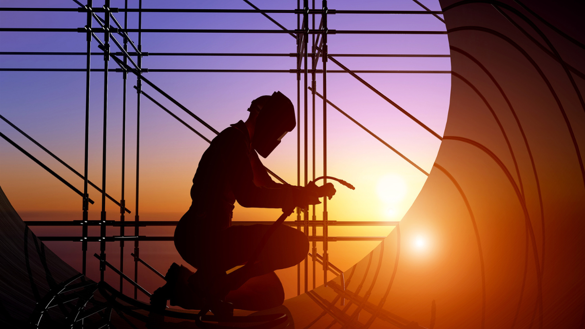 Saldatore professionale che lavora in ambiente industriale durante l'autunno indossando DPI completi per la sicurezza